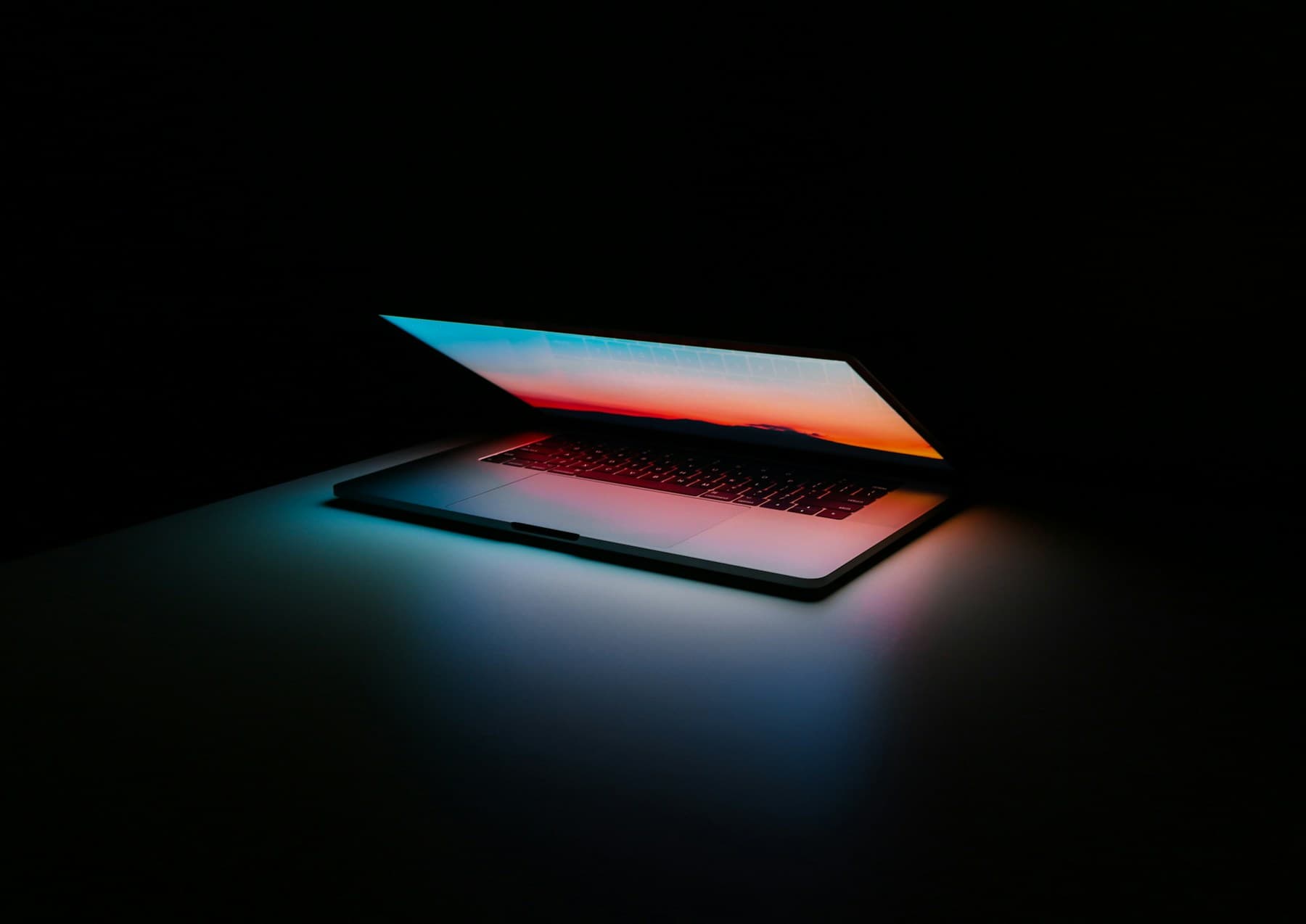 An open laptop in a dark room, its screen the only light